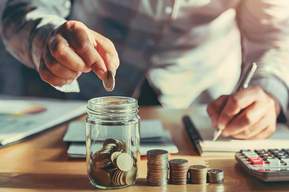 Person putting coins into a glass jar