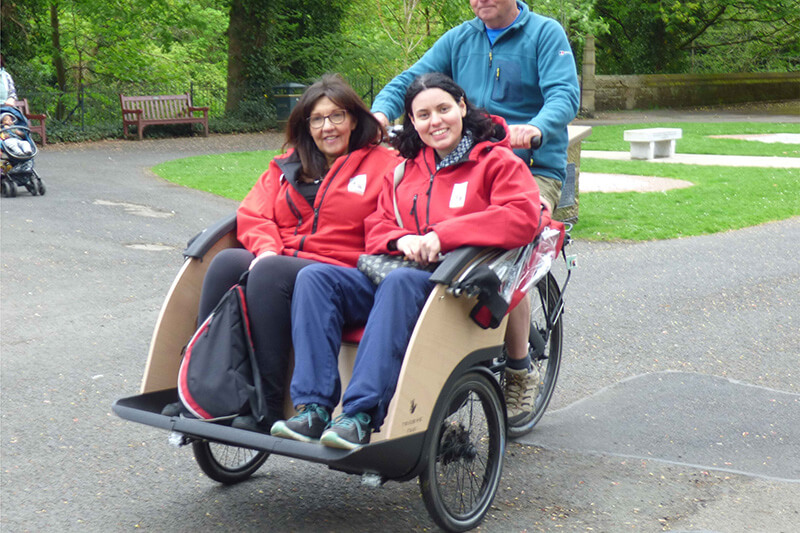 two people sitting in a rickshaw type bike