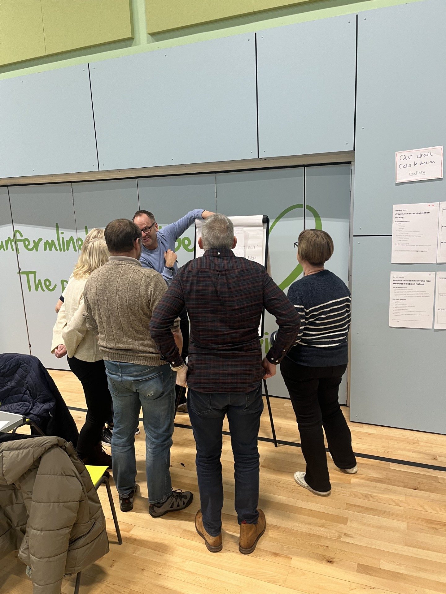 Members of the Dunfermline New City Assembly gather around a whiteboard to discuss ideas.