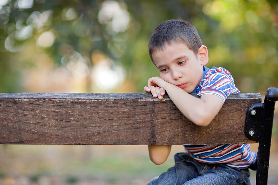 sad looking boy on a bench