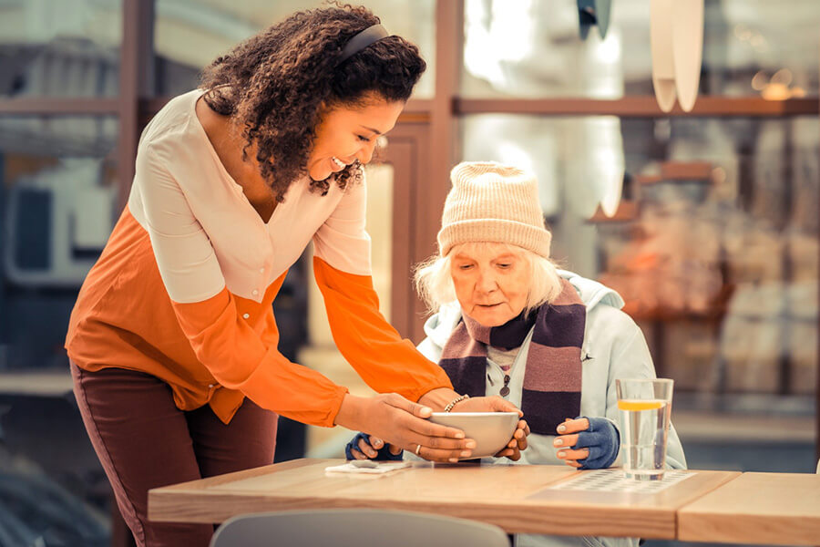 older woman being served a bowl of soup