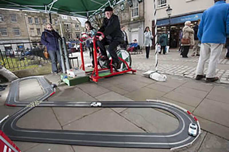 Person cycling to power electric model cars  